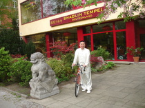Gran Maestro Shi Yong Dao con bicicleta frente al Templo Shaolin Alemania